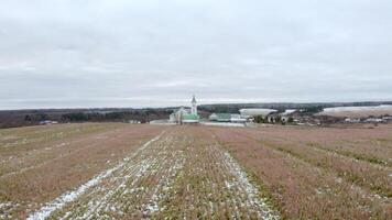 Initial winter. Clip.View from a drone on a landscape with snowy grass in a field where there is a temple with a golden cross on a golden dome against the blue sky. video