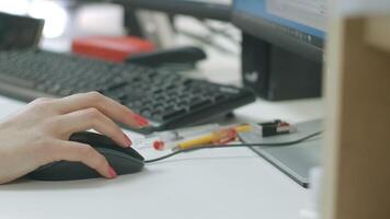 Close-up of woman working at computer in office. Creative. Woman drives computer mouse at desk. Woman's hand with manicure howls with computer mouse video