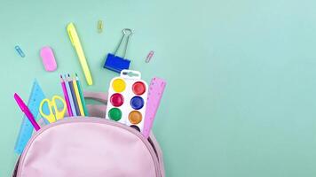 School supplies are collected in a backpack. Back to school concept. Pastel colors stop motion animation flat lay copy space for your text video
