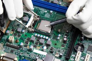 he close up image of technician squeezing the fresh thermal paste compound on the top of cpu in the socket. the concept of computer hardware, repairing, upgrade and technology. photo