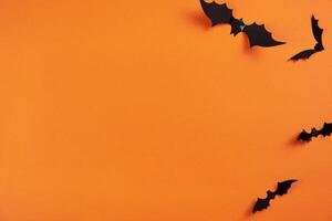 Happy halloween flat lay mockup with black bats on orange background. Holiday concept composition. Top view. Copy space. photo