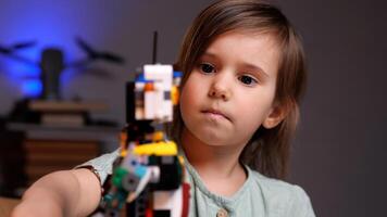 Little girl playing with robot from plastic bricks photo