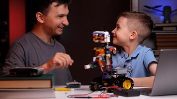 Father and son building robot and programming it at home photo