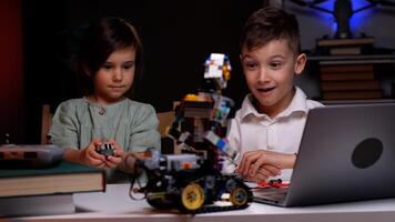 Two kids programming robot from laptop using wireless controller photo