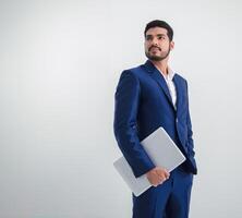 Business man portrait asian one person wearing a blue suit handsome standing looking success committed hand holding computer and notebook ready for work inside room office, with white background photo