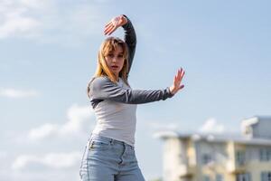 Young Dancer Engaging in Expressive Movement Against a Clear Sky in Urban Environment photo