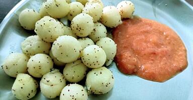 Suji appe or rice appe or appam, an Indian snack with onion, peanuts and tamarind dip photo