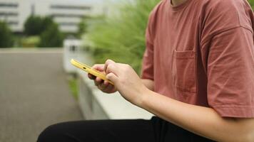 Happy pretty girl university student user holding cell phone using education tech apps looking at smartphone texting messages standing outside. Mobile online applications concept. video