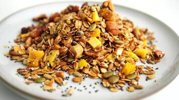 Healthy organic granola breakfast flakes with almonds, cashew nuts walnuts, hazelnuts, pumpkin seeds and cranberries circle rotation close up top view. video