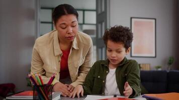 African American family talking little son boy child kid at home table studying learning distant education study learn difficult homework problem trouble talk argue with mother woman argument conflict video