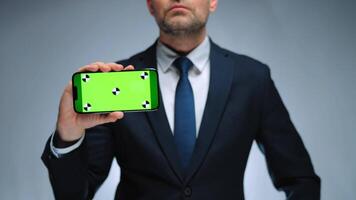 Man shows smartphone with green screen chroma key smartphone on camera. video