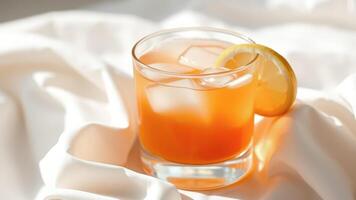 Glass of orange juice with ice and lemon slice on white fabric photo