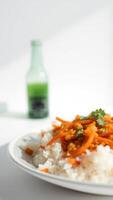 Close up of rice with carrots and cilantro on a white plate photo