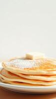 Closeup of a Stack of Pancakes with Powdered Sugar and Butter on Top photo