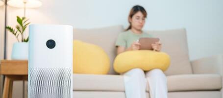 Air Purifier with woman relax and use tablet on sofa. Purification system for filter and cleaning dust PM2.5 HEPA and virus in home. Allergy, Pure air, health, Wellness lifestyle and Air Pollution photo