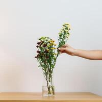 Woman hand arrange Colorful flowers bouquet in mason jar on table background. Happy day with fresh flower photo