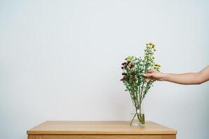 Woman hand arrange Colorful flowers bouquet in mason jar on table background. Happy day with fresh flower photo