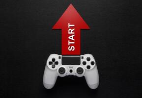 white modewrn gamepad and red arrow with strart on a dark background photo