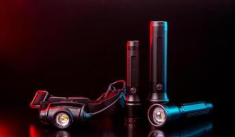 Head and pocket flashlights on a dark back. Modern lanterns illuminated with red-blue light. photo