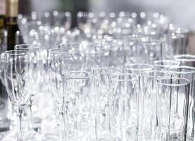 Lots of different empty glasses on the table. Preparing for a banquet, holiday or wedding. Blurred back. photo