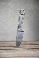 A knife with a metal handle made from a wrench. A tool weapon is stuck into a wooden surface. Light back. photo
