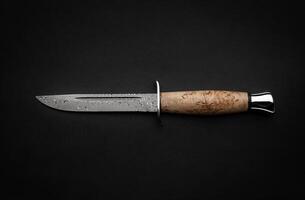 Damascus hunting knife with a wooden handle on a dark background. Melee weapons for hunting and self-defense. The instrument of crime. photo