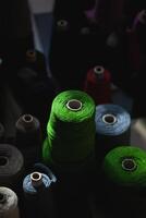 Skeins of yarn folded side by side. Multicolored cones with threads of yarn lie in the twilight, only slightly illuminated. photo