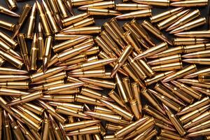A pile of ammunition for weapons. Cartridges for machine guns and carbines. Background from new shiny cartridges. photo