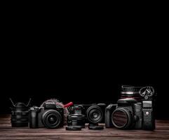 Different modern cameras and lenses on a wooden table. Technique for shooting photos and videos. blogger kit. Postcard concept for photographer and videographer.