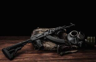 Soviet carbine in modern body kit. Weapons of Russia and the Soviet Union. Classic Soviet AK assault rifle and gas mask on a wooden back. photo