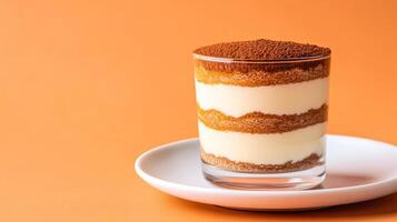 Exquisite dessert of layered tiramisu in a glass, dusted with cocoa powder, placed on a white plate with clear empty space for text, warm gradient background photo