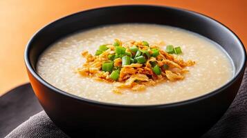 Warm autumn Asian dish featuring a bowl of savory pumpkin congee, topped with crispy shallots and fresh green onions, set against a gradient background shifting from burnt orange to deep brown photo
