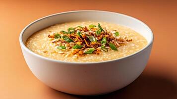 Warm autumn Asian dish featuring a bowl of savory pumpkin congee, topped with crispy shallots and fresh green onions, set against a gradient background shifting from burnt orange to deep brown photo