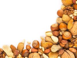 Background of mixed nuts - hazelnuts, almonds, walnuts, pistachios, peanuts, pine nuts peeled and not peeled - vertical with copy space. Isolated one edge. Top view or flat lay photo