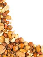 Background of mixed nuts - hazelnuts, almonds, walnuts, pistachios, peanuts, pine nuts peeled and not peeled - vertical with copy space. Isolated one edge. Top view or flat lay photo