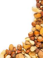 Background of mixed nuts - hazelnuts, almonds, walnuts, pistachios, peanuts, pine nuts peeled and not peeled - vertical with copy space. Isolated one edge. Top view or flat lay photo