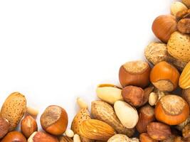 Background of mixed nuts - hazelnuts, almonds, walnuts, pistachios, peanuts, pine nuts peeled and not peeled - vertical with copy space. Isolated one edge. Top view or flat lay photo