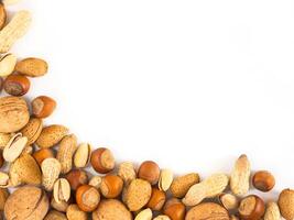 Background of mixed nuts - hazelnuts, almonds, walnuts, pistachios, peanuts, pine nuts peeled and not peeled - vertical with copy space. Isolated one edge. Top view or flat lay photo