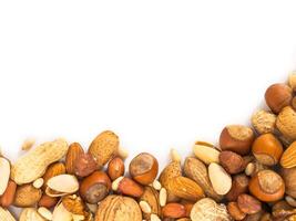 Background of mixed nuts - hazelnuts, almonds, walnuts, pistachios, peanuts, pine nuts peeled and not peeled - vertical with copy space. Isolated one edge. Top view or flat lay photo