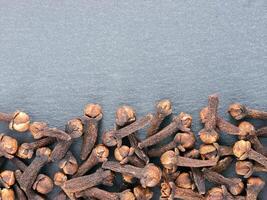 Cloves spice on gray slate background with copy space. Isolated one edge. Top view or flat lay. photo