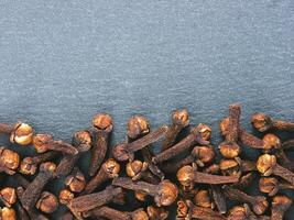 Cloves spice on gray slate background with copy space. Isolated one edge. Top view or flat lay. photo
