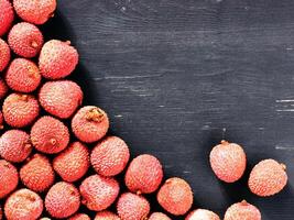 lichee fruit on dark wooden background close up with copy space. Top view or flat lay photo