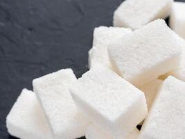 background of sugar cubes. White cube sugar on black background. White sugar close up with copy space photo