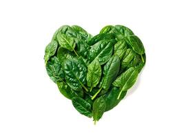 Heart shape made from spinach leaves, isolated photo