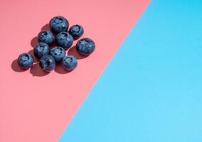 Blueberry on pink and blue background, copy space photo