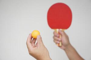 Selective focus on the orange ball on hand with serving table tennis racket. Concept, sport equipment. Exercise or workout tool. Competitive game sport. Playing Ping pong photo
