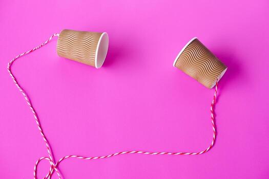 DIY paper cups with string on pink background. Concept, telephone toy. Concept, telephone toys which apply with science knowledge about vibration sound through straining strings causing us to hear. photo
