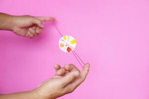Closeup man hand plays the diy spinning wheel toy, made from bottle cap and string. Spinning motion photo. Concept, retro toy which apply with science knowledge. Potential energy photo