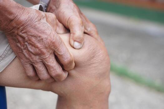 Close up elderly man hurt his knee, use hands to massage knee. Concept, health care and health problems. Artritis symptom. Suffering from knee pain. Tendon problems and Joint inflammation photo