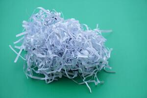 Pile of sliced used paper to be small stripes, prepare to recycle process on green background. Concept, Waste or garbage management. Documents shredded for security purposes. photo